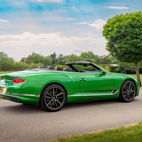 A green Bentley Continental GTC convertible parked up on a country road. 