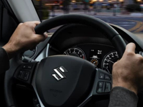 Image of someone with their hands on the steering wheel of a Suzuki.