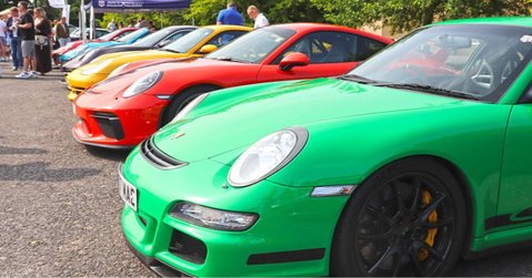 Line of colourful Porsche sports cars including green, red, and yellow models displayed at Simply Porsche 2025, Beaulieu Motor Museum.