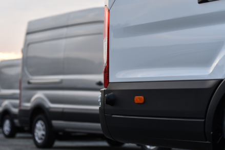 Photograph of the rear section of 3 white vans in a staggered row