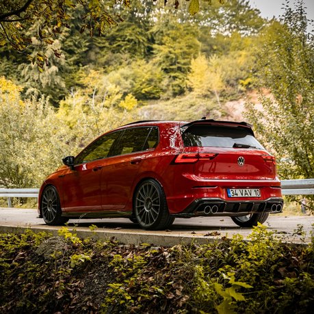 A red Golf R parked up under some trees.