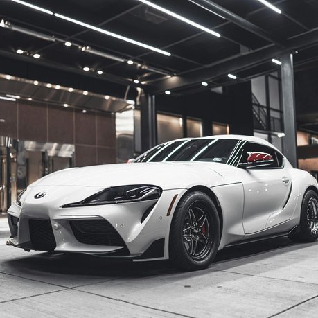The modern Toyota Supra in white outside a swish hotel.