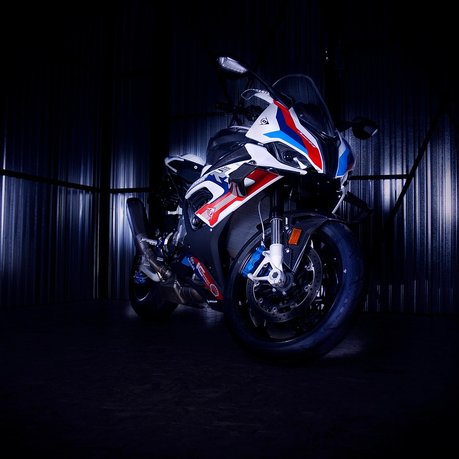 A BMW superbike on display with a back background and moody lighting.