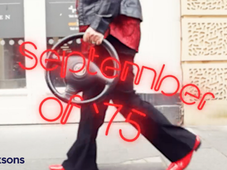 Image of someone holding a steering wheel while wearing a 70s-esque outfit and text that says "September of '75".