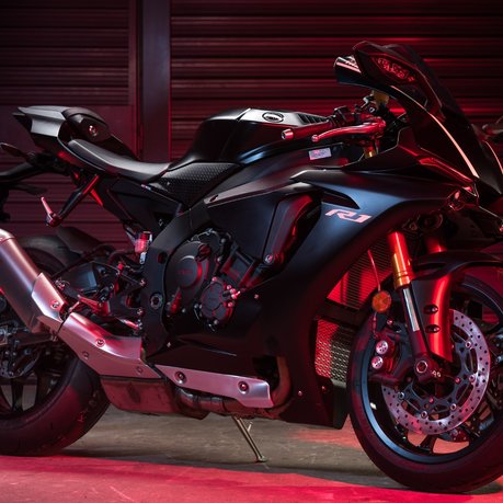 A black Yamaha R1 in moody red lighting.