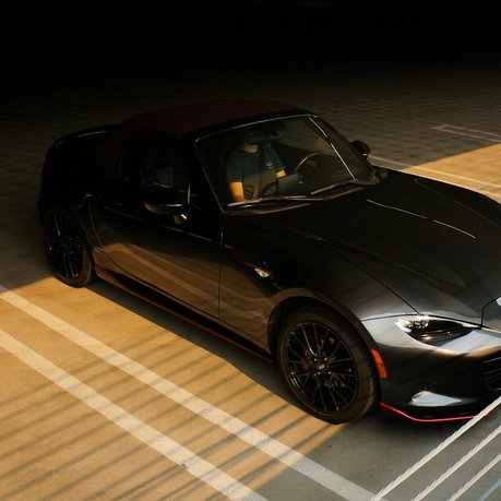 A black Mazda MX-5 in a dark parking lot.