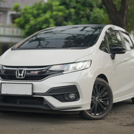 A white Honda Jazz parked up. This one is an example of an overseas model.