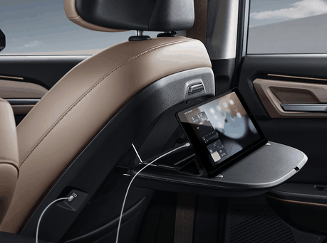 Image of the back of a seat with a tablet plugged in and sitting on the tray table.