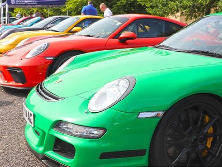 Line of colourful Porsche sports cars including green, red, and yellow models displayed at Simply Porsche 2025, Beaulieu Motor Museum.