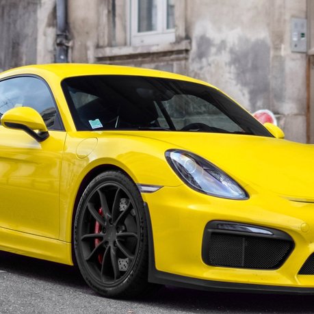 A bright yellow Porsche Cayman GT3 parked up on a French street.